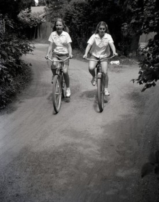 Two Teenage Girls Riding Bikes on Dirt Track Fine Art Print