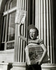 Boy Selling Newspapers in Front of a Building Fine Art Print