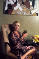 Elke Sommer sitting on a chair holding a glass photo print.
