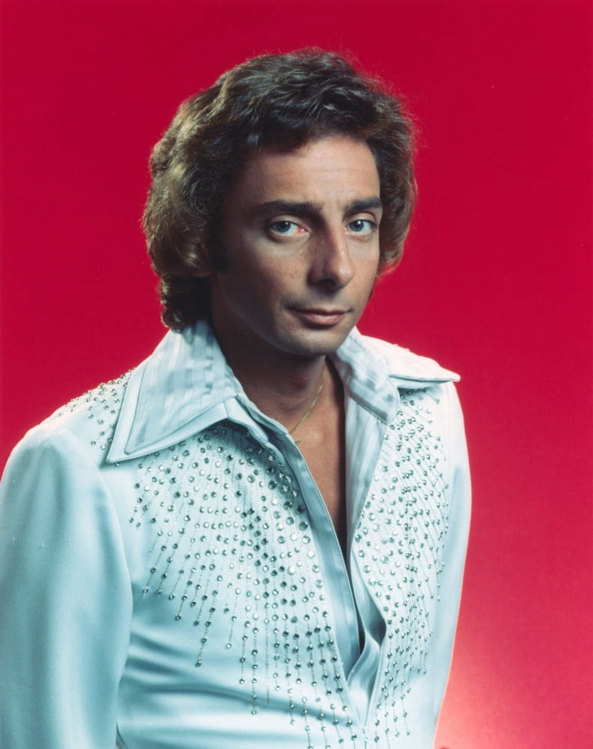 Close-up portrait photo print of Barry Manilow in white sleeves with a red background.