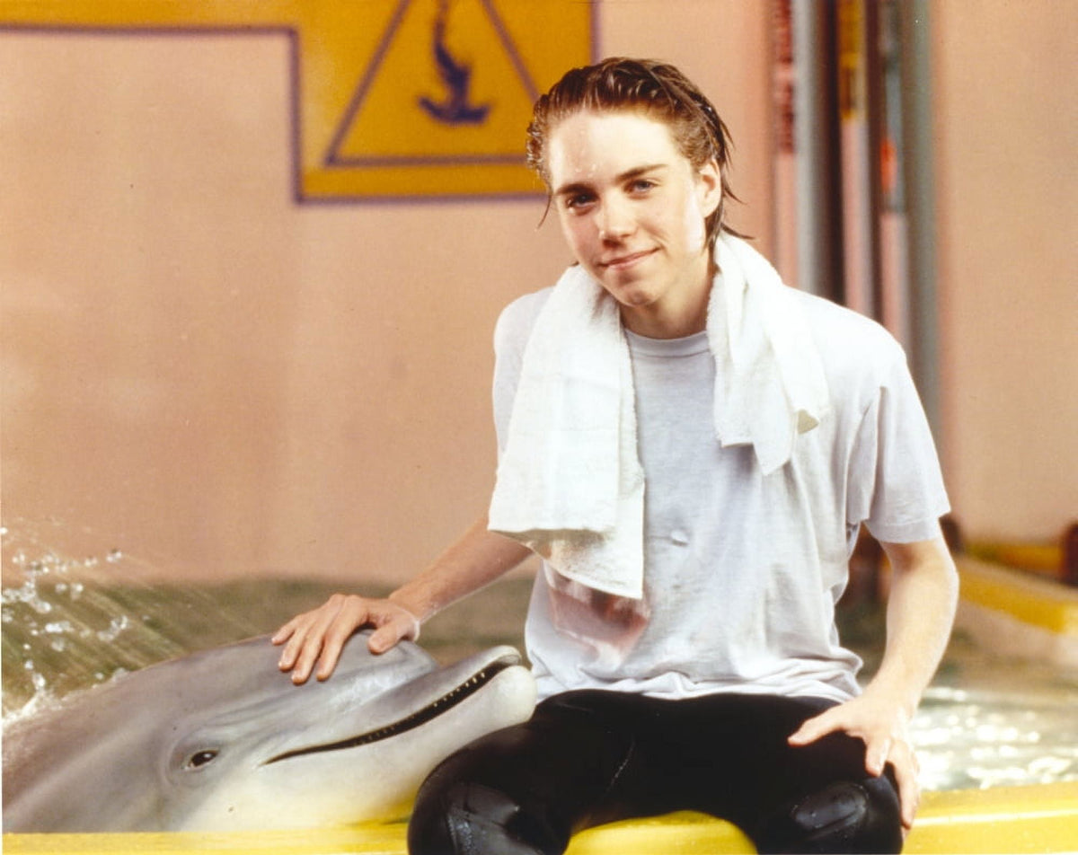 Jonathan Brandis posing with a dolphin photo print