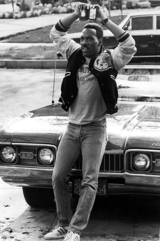 Eddie Murphy holding up a police badge photo print.