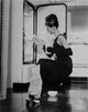 Audrey Hepburn holding ballet shoes and feeding the cat photo print