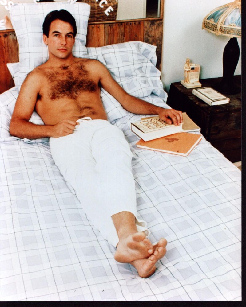 Mark Harmon shirtless photo print lounging on bed in white pants.