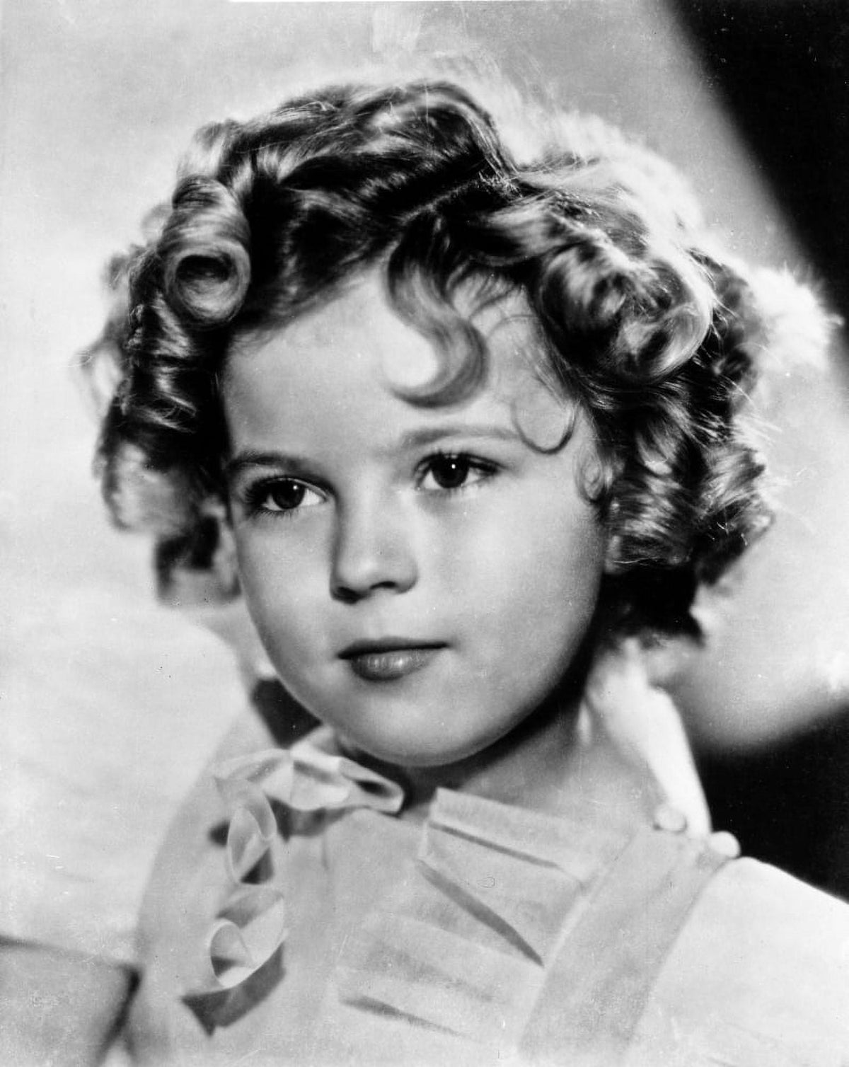 Close-up portrait photo print of Shirley Temple in a cap-sleeve white dress.