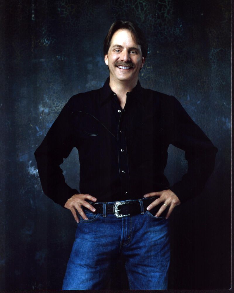 Jeff Foxworthy photo print in black top and jeans, hands on hips.