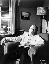 James Dean seated on a couch in a white shirt and black pants photo print.