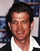 Close-up portrait photo print of Chris Isaak in black coat with white collar.