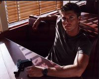 Jensen Ackles photo print in booth with gun on table.