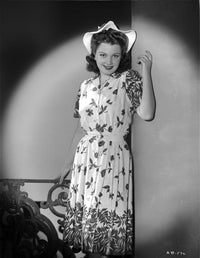 Anne Baxter smiling in a printed dress leaning on a post photo print