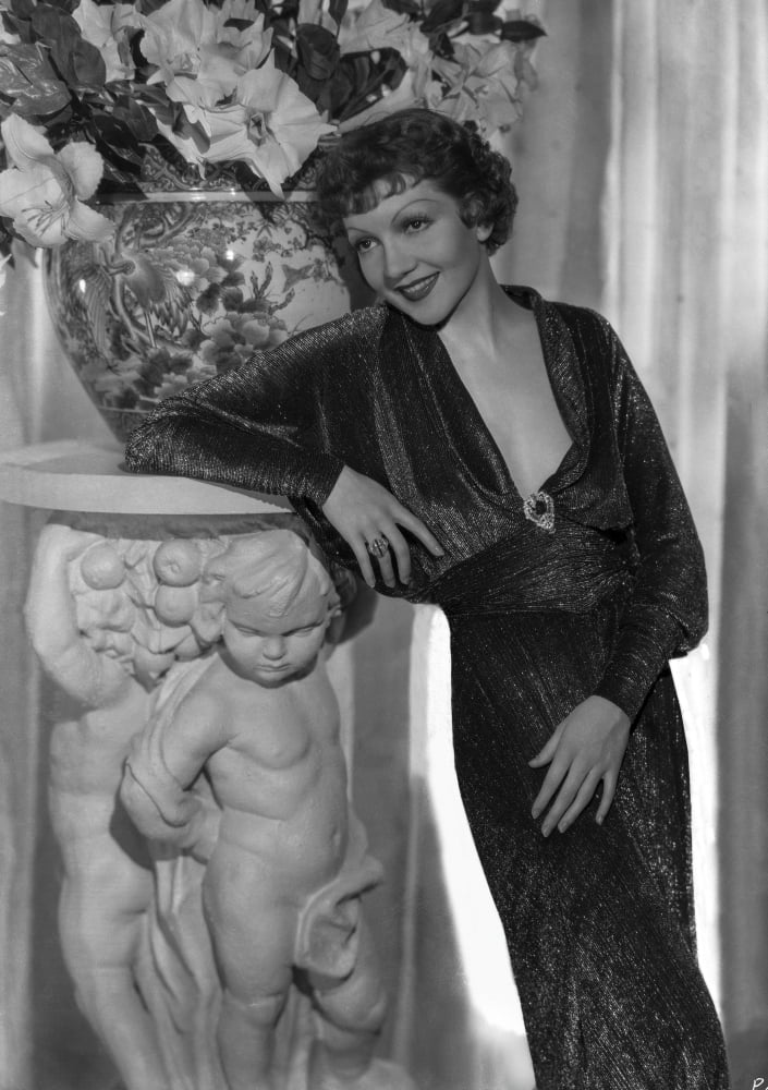 Claudette Colbert leaning on statue wearing a black dress photo print