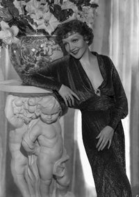 Claudette Colbert leaning on statue wearing a black dress photo print