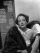 Classic photo print of Joan Crawford looking away from the camera while leaning on a chair.