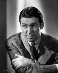 James Stewart portrait in black ribbed suit with arms crossed.