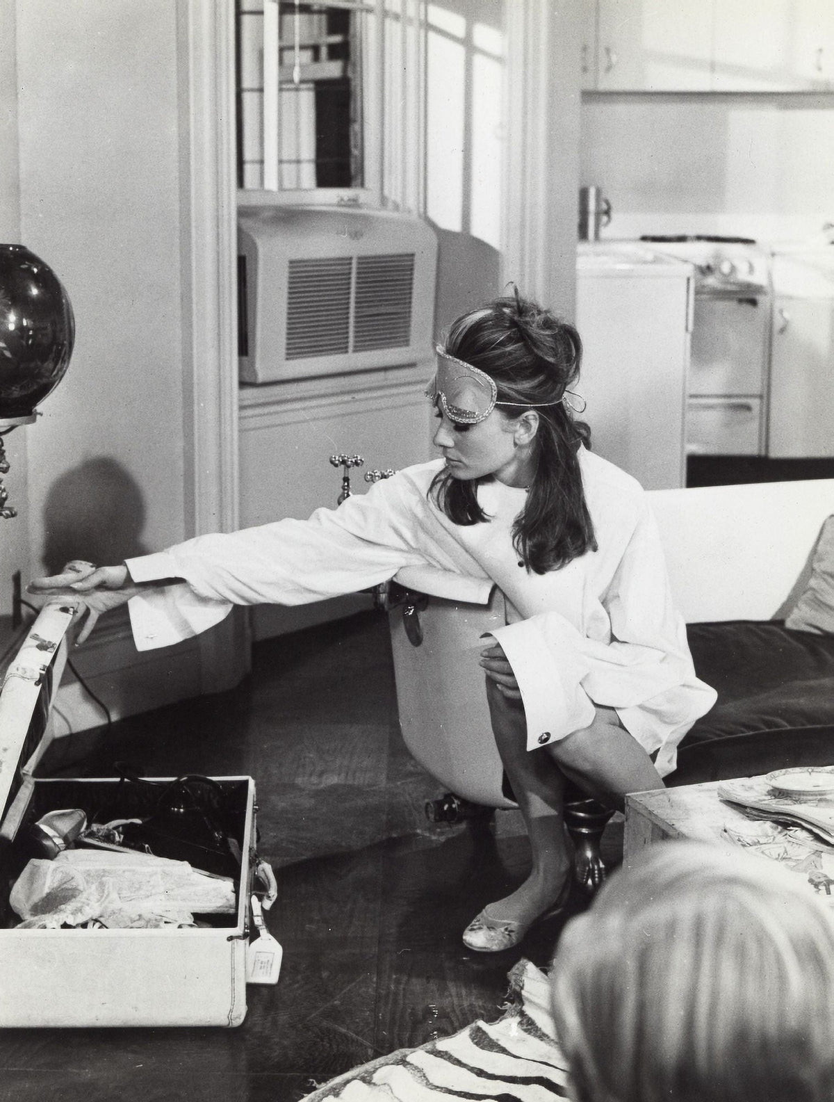 Audrey Hepburn film still photo print wearing an eye mask and packing a suitcase.