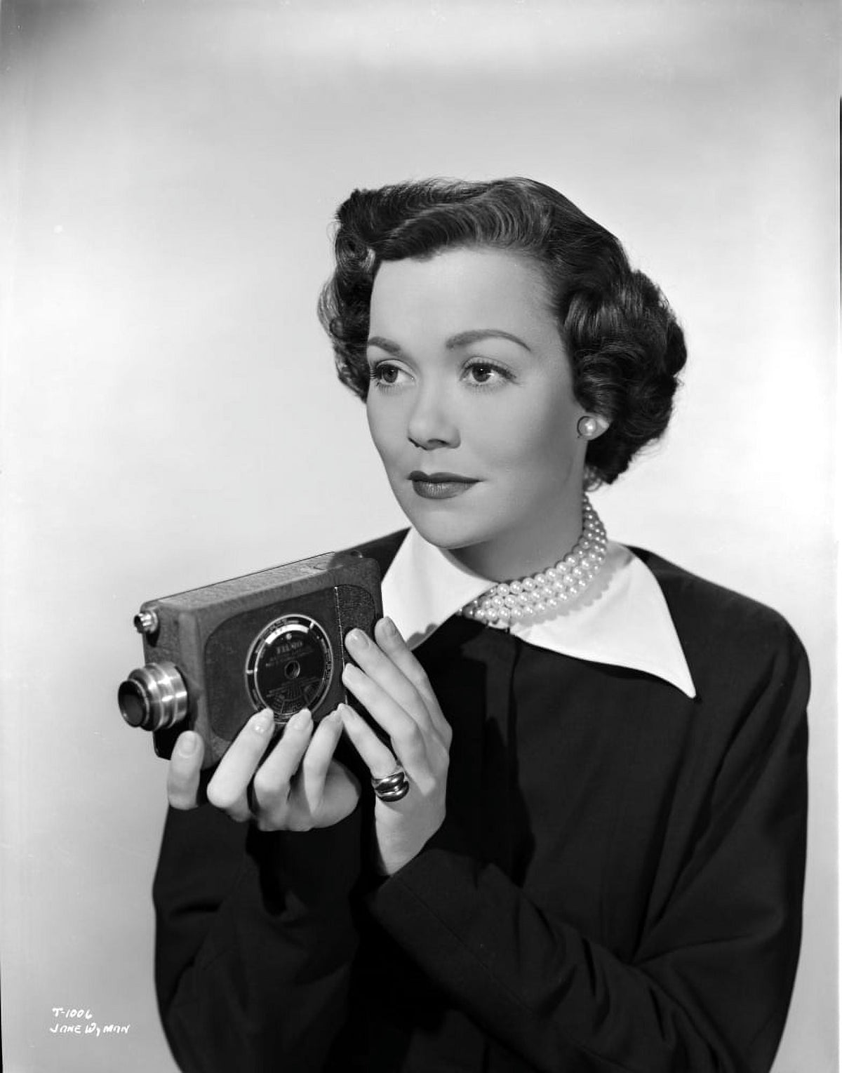 Jane Wyman portrait photo print in long sleeve shirt with white collar and pearl necklace, holding a camera.