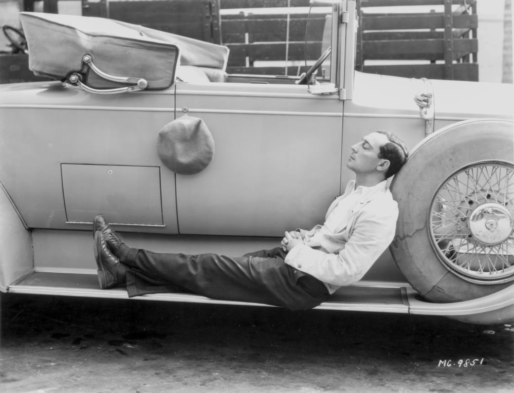 Buster Keaton sleeping on a car photo print