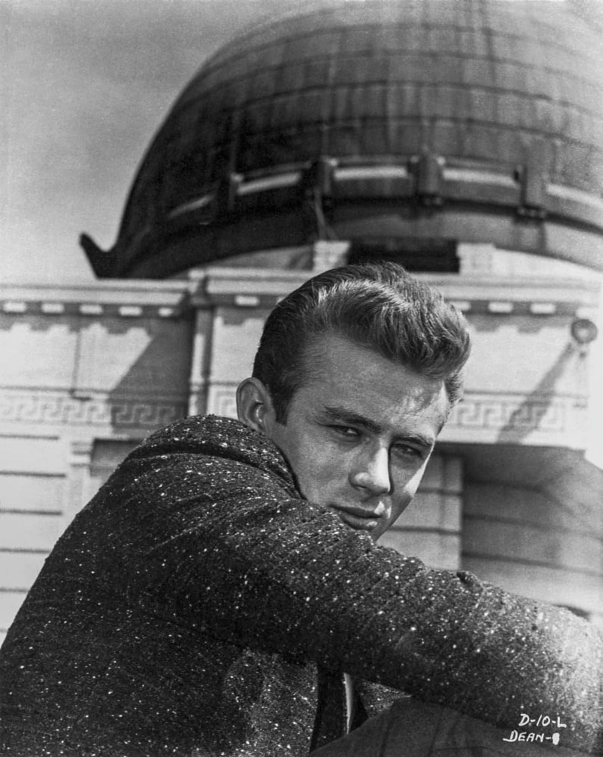 James Dean portrait in black sequin suit with arms on knees.