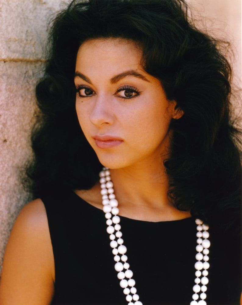 Elegant portrait of Rita Moreno in a black dress with a necklace.