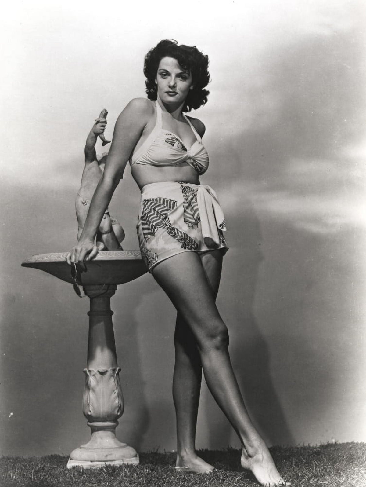 Jane Russell in white silk swimsuit photo print beside a marble figure.