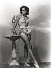 Jane Russell in white silk swimsuit photo print beside a marble figure.