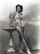 Jane Russell in white silk swimsuit photo print beside a marble figure.