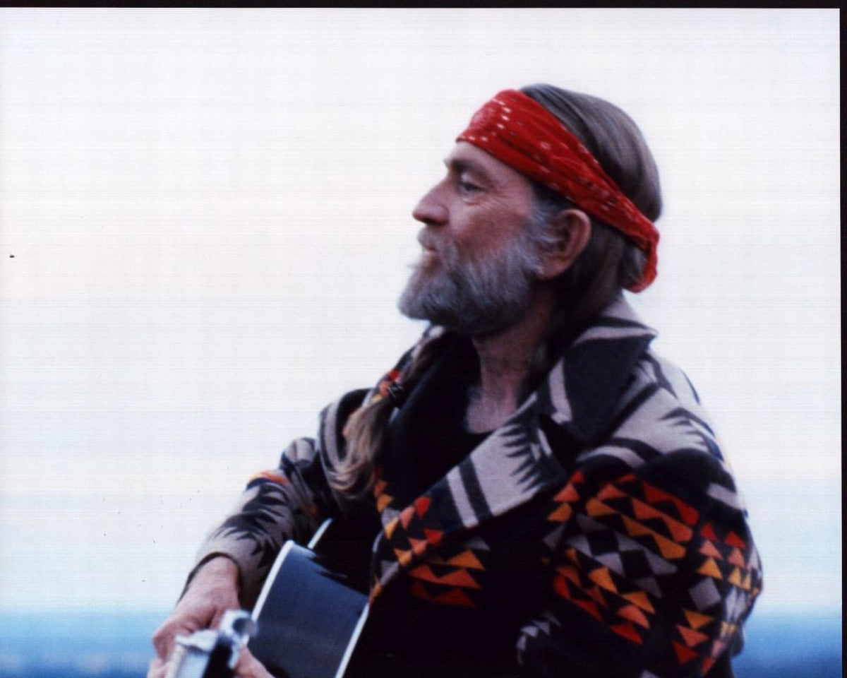 Willie Nelson playing guitar in multicolored jacket photo print.