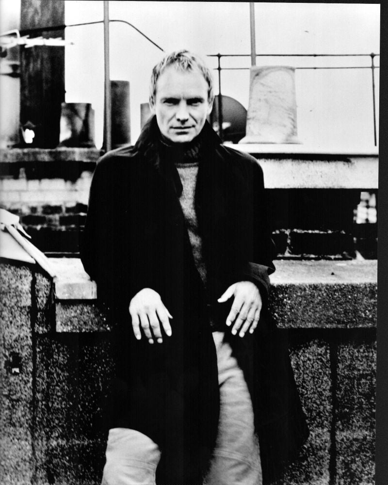 Black and white photo print of Sting leaning on a wall wearing a long coat.
