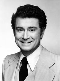 Close-up portrait of Regis Philbin in black and white wearing a formal coat.
