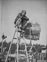 Steve McQueen seated on a ladder in black and white photo print